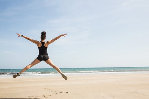 Fit woman leaping on the sand at the beach