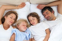 Family sleeping together lying in the bed