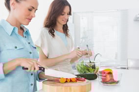 Women preparing salad together in the kitchen