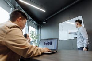 Employee on left on laptop and employee on right presenting