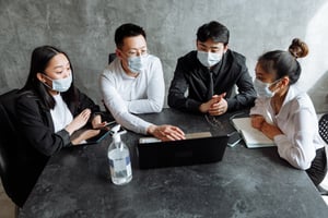 5 people in face masks surrounding a laptop