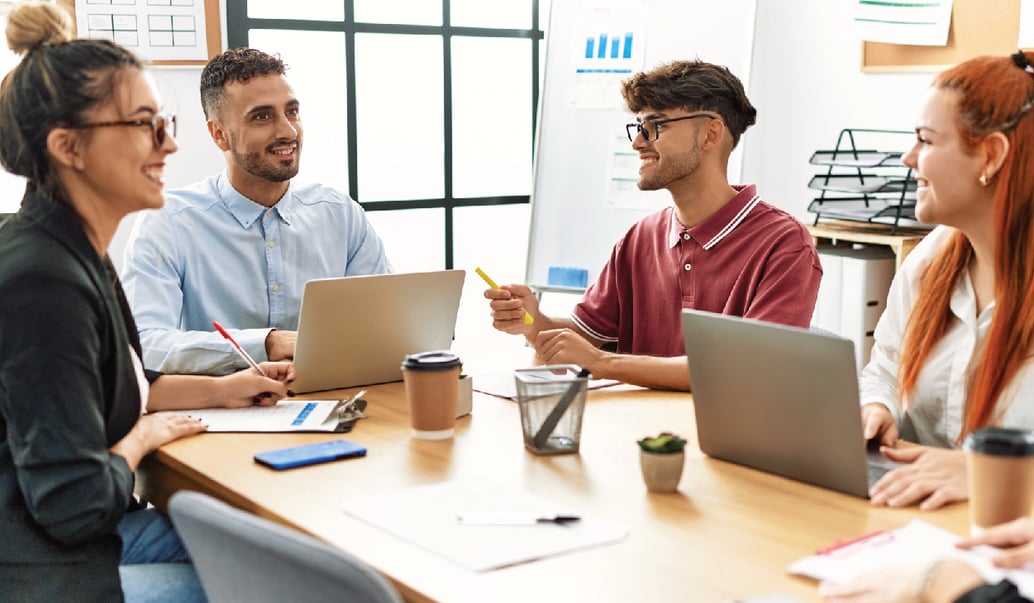 Four diverse employees talk about ways to improve their health and wellness program in a conference room.