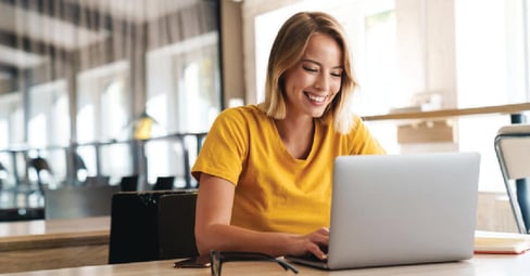 Woman on laptop wearing yellow shirt