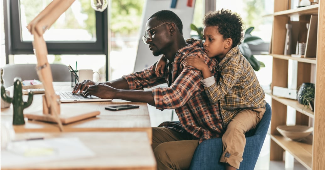 Father working from home with son on his back