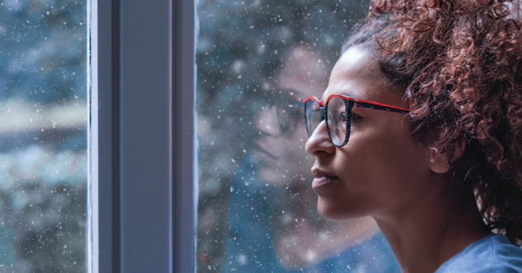 Woman with glasses looking outside at snow