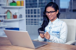 Smiling Asian woman with eyeglasses using smartphone in office-1.jpeg