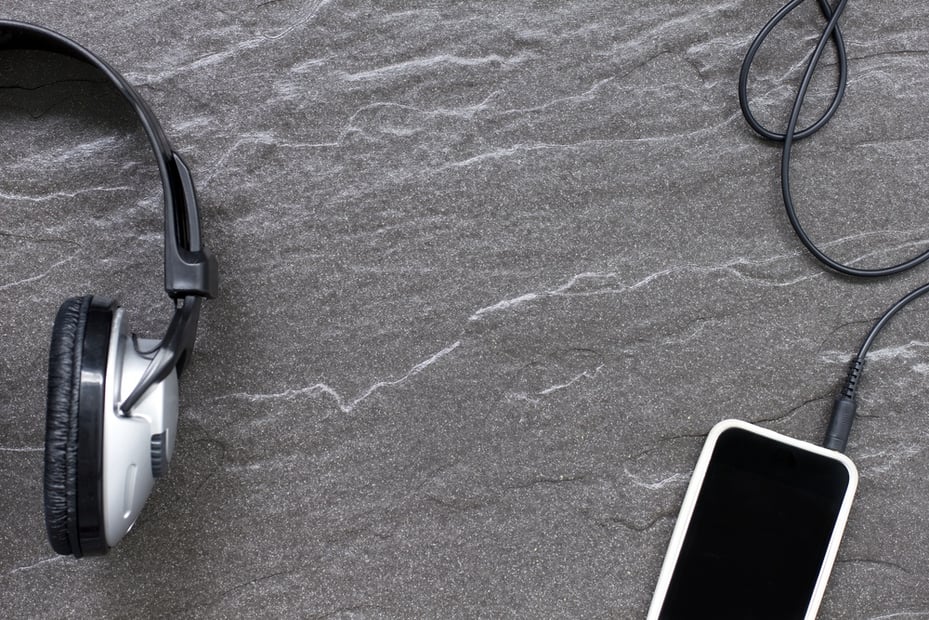 Music headphones on a detailed stone surface with a music player attached