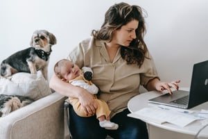 busy mom holding baby while on computer