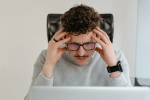 man looking down at laptop stressed